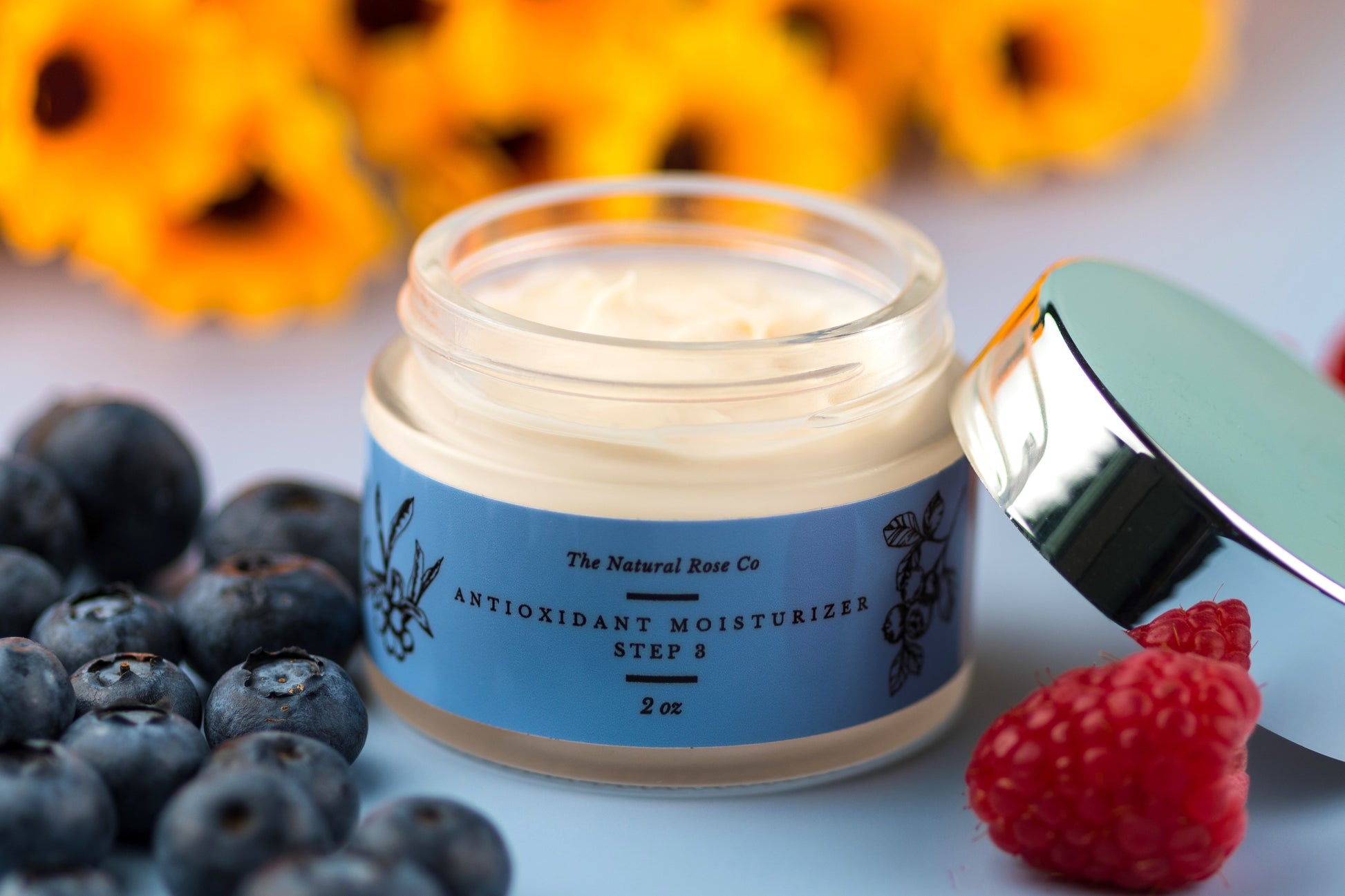 The Natural Rose natural skincare antioxidant cream in jar with blueberries and raspberries around